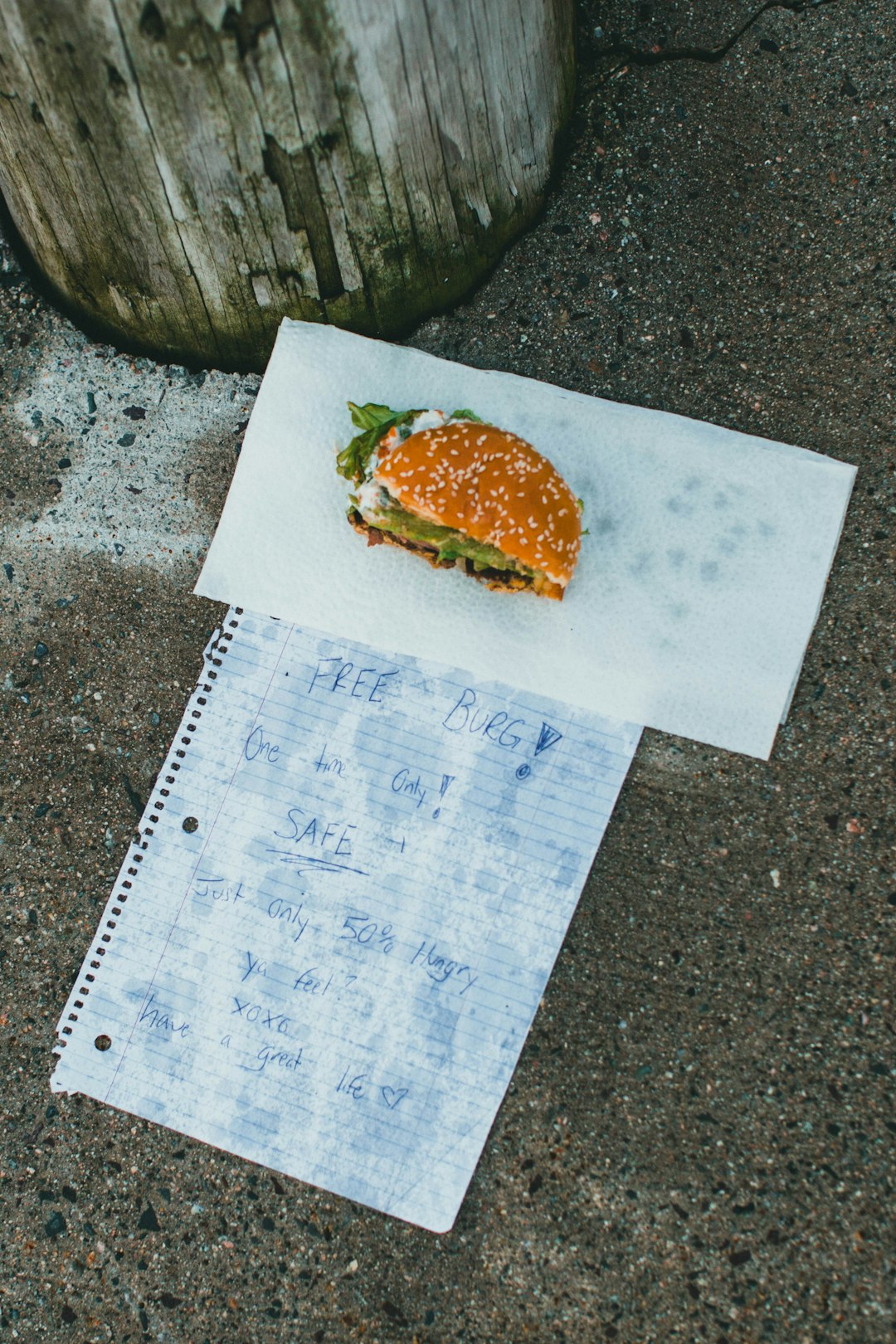 burger on white paper beside green and brown vegetable