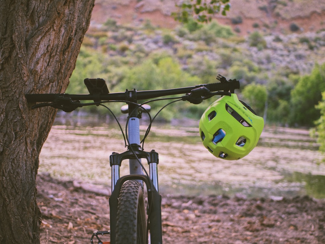 green and black bicycle helmet on black bicycle handle bar