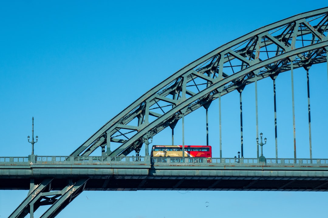 red and white bridge under blue sky during daytime, Red Bus crossing the bridge