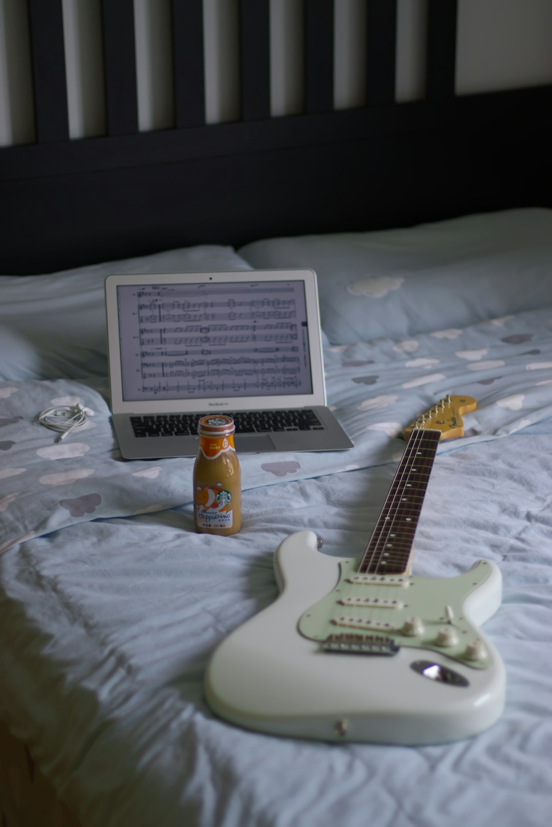white stratocaster electric guitar on white bed linen