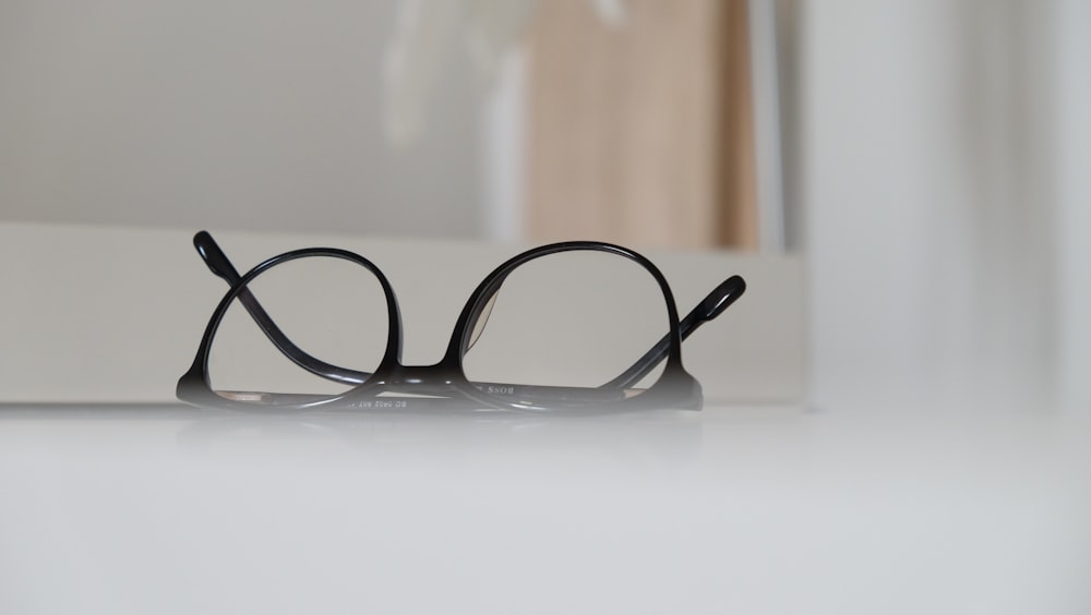 black framed eyeglasses on white table