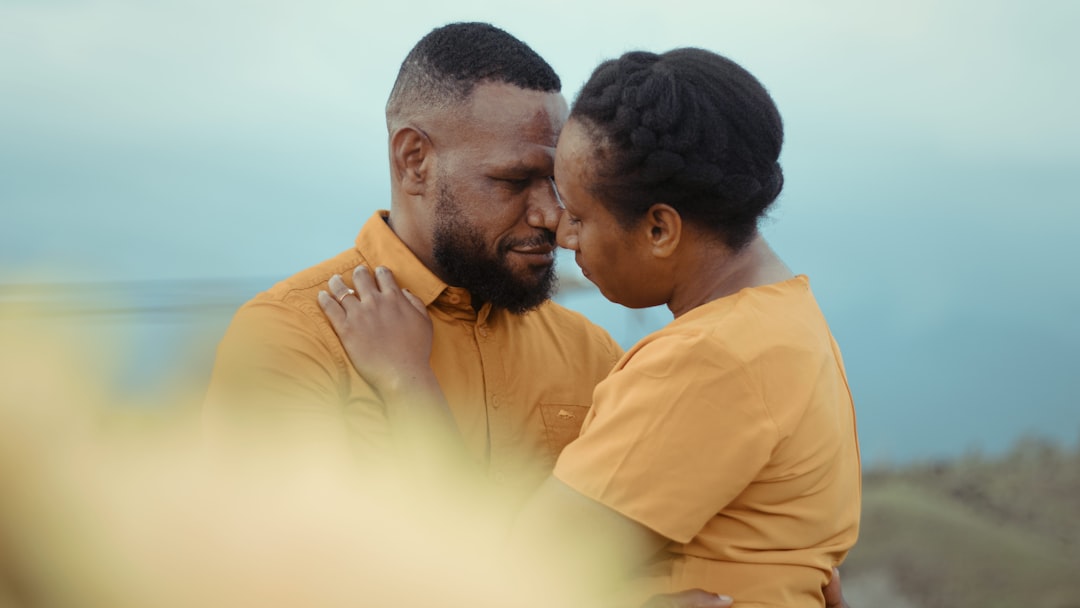 man in yellow dress shirt kissing woman in white dress