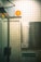 A tiled wall featuring a directory sign listing various business names and room numbers in a building. There is a security camera sign with an orange logo attached above. The setting appears to be an indoor corridor or lobby area with a glass door on the left side.