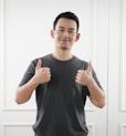 man in black tank top standing near white wall