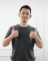 man in black tank top standing near white wall