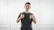 man in black tank top standing near white wall