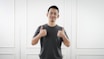 man in black tank top standing near white wall
