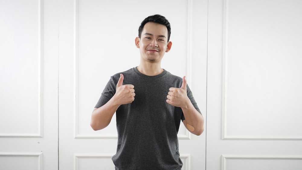 man in black tank top standing near white wall