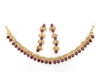 A bridal set featuring a choker and matching earrings adorned with red and white stones, perfect for festive occasions.