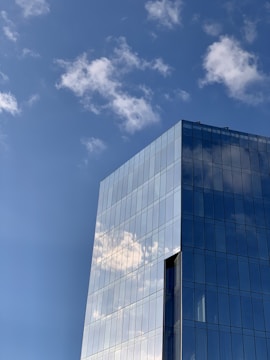 Photo of a sleek glass office skyscraper against a clear blue sky.