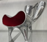 Vibrant red metal chair frame coated with a glossy powder finish, ready for delivery.