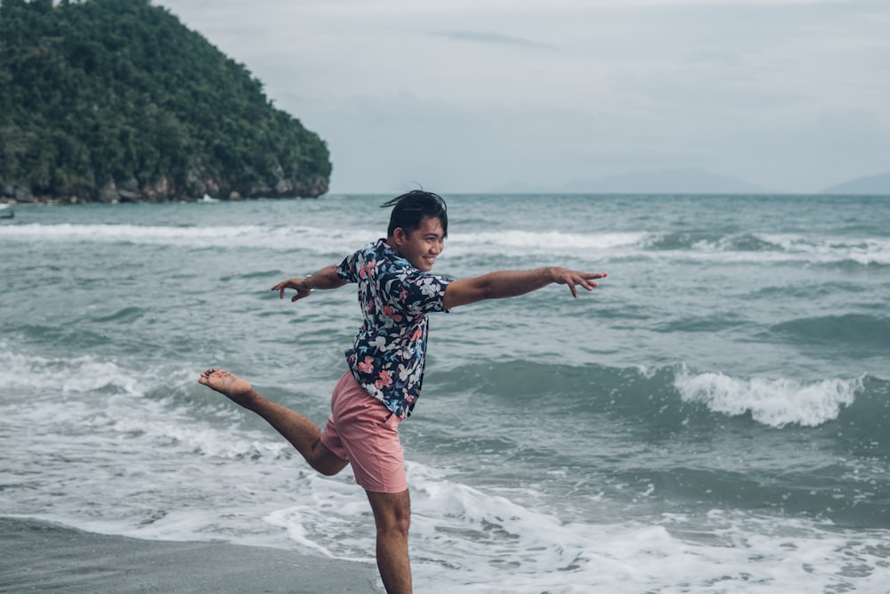 girl in blue and white floral shirt and pink shorts standing on beach during daytime