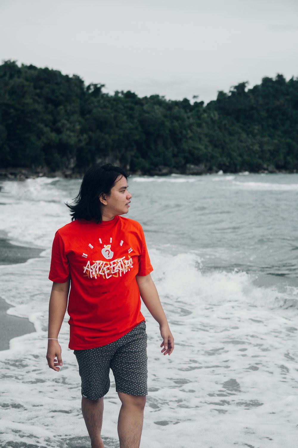 woman in red crew neck t-shirt standing on beach during daytime