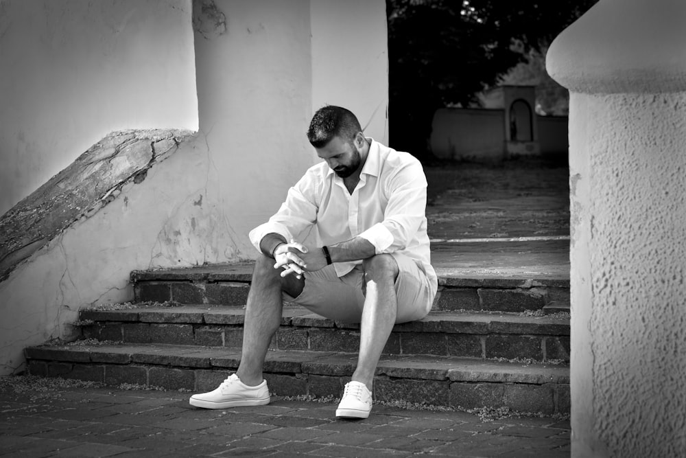 man in white dress shirt sitting on concrete stairs