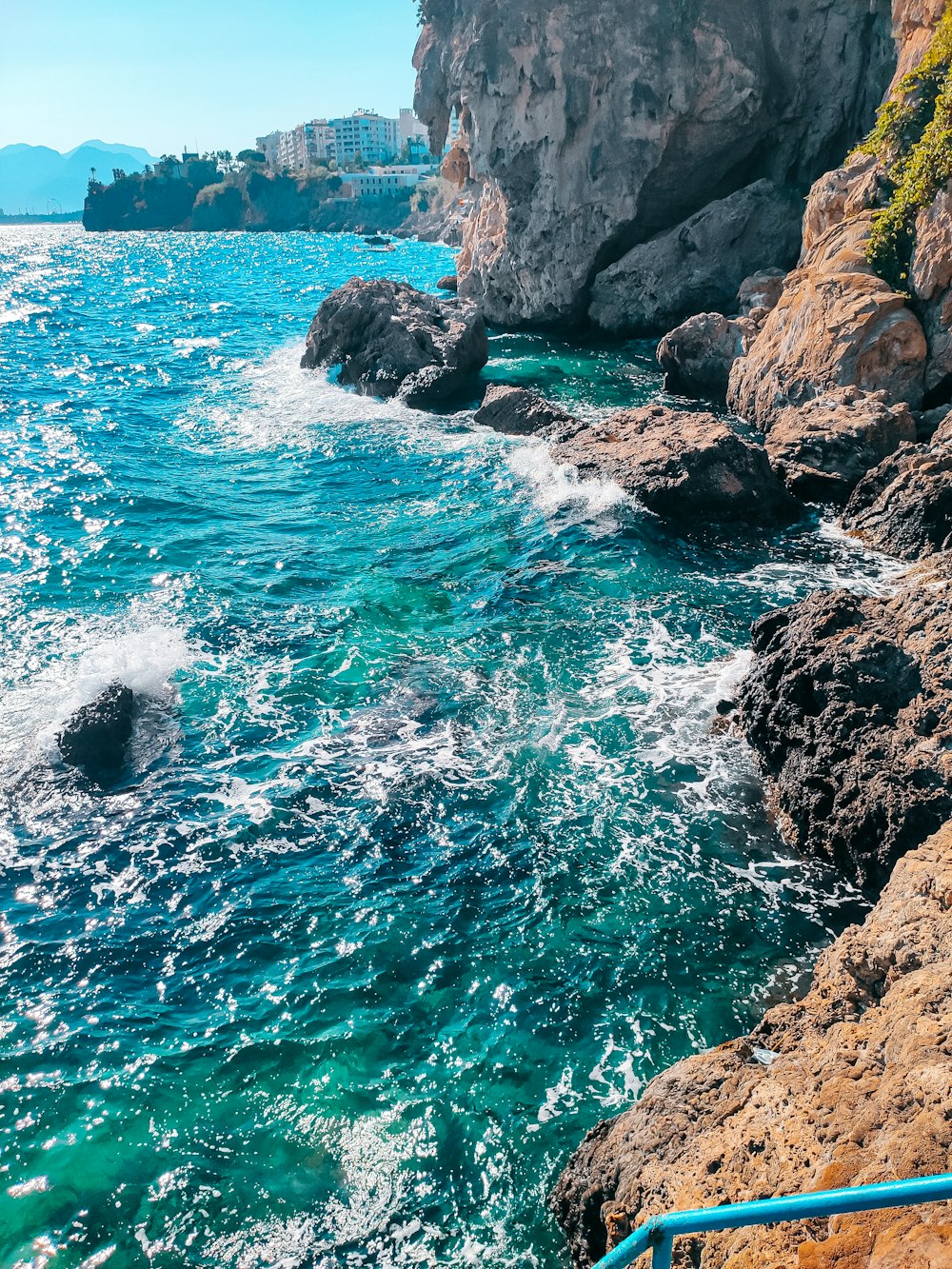 brown rocky mountain beside blue sea during daytime