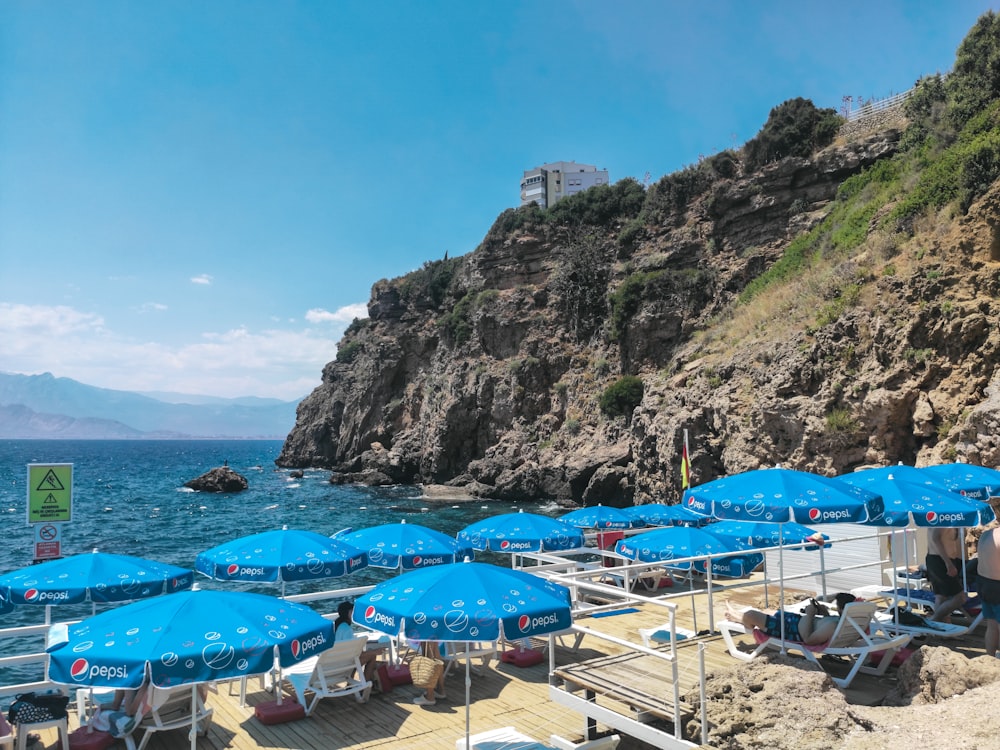 a group of blue umbrellas sitting on top of a beach