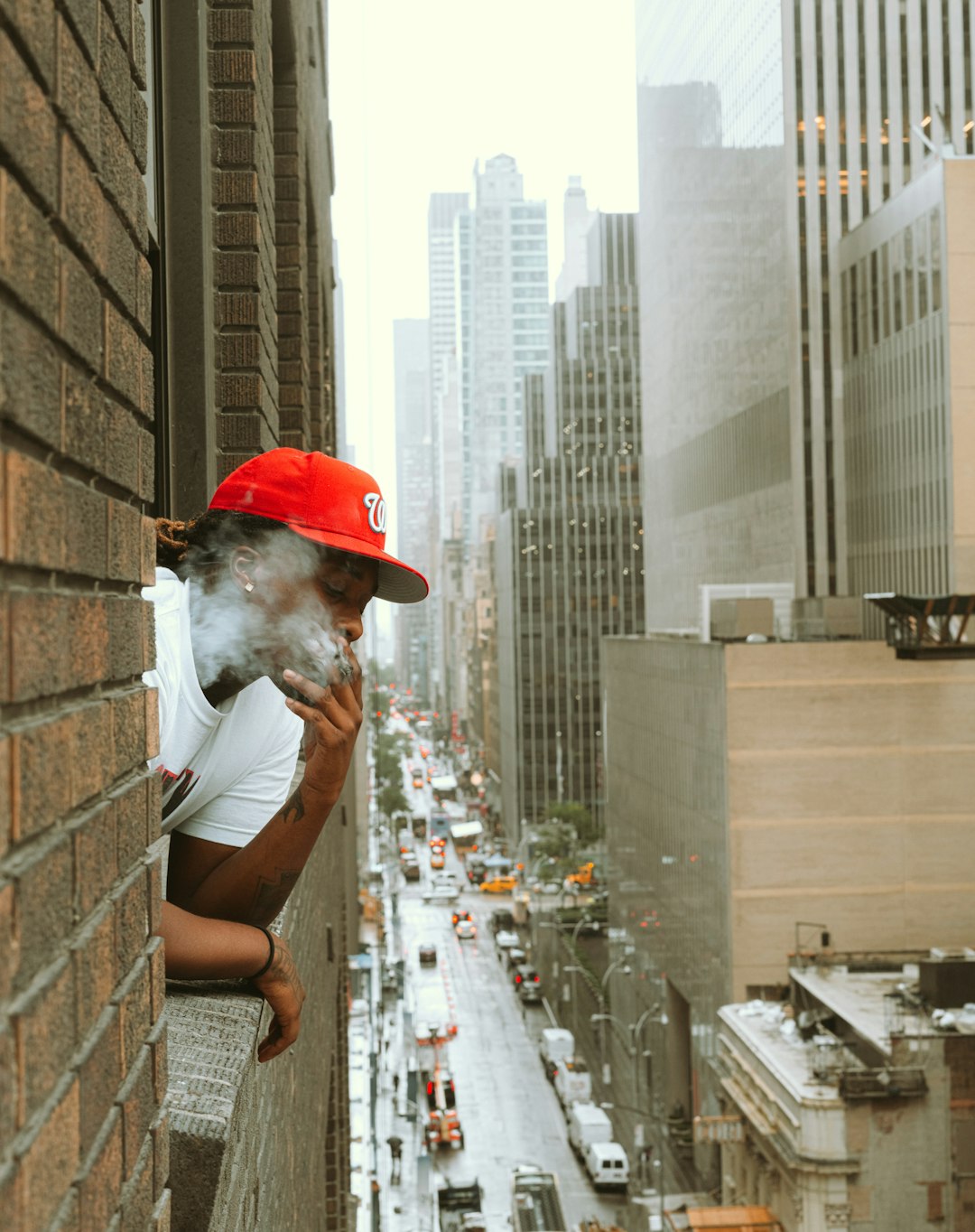 man in white t-shirt and red cap sitting on concrete bench during daytime