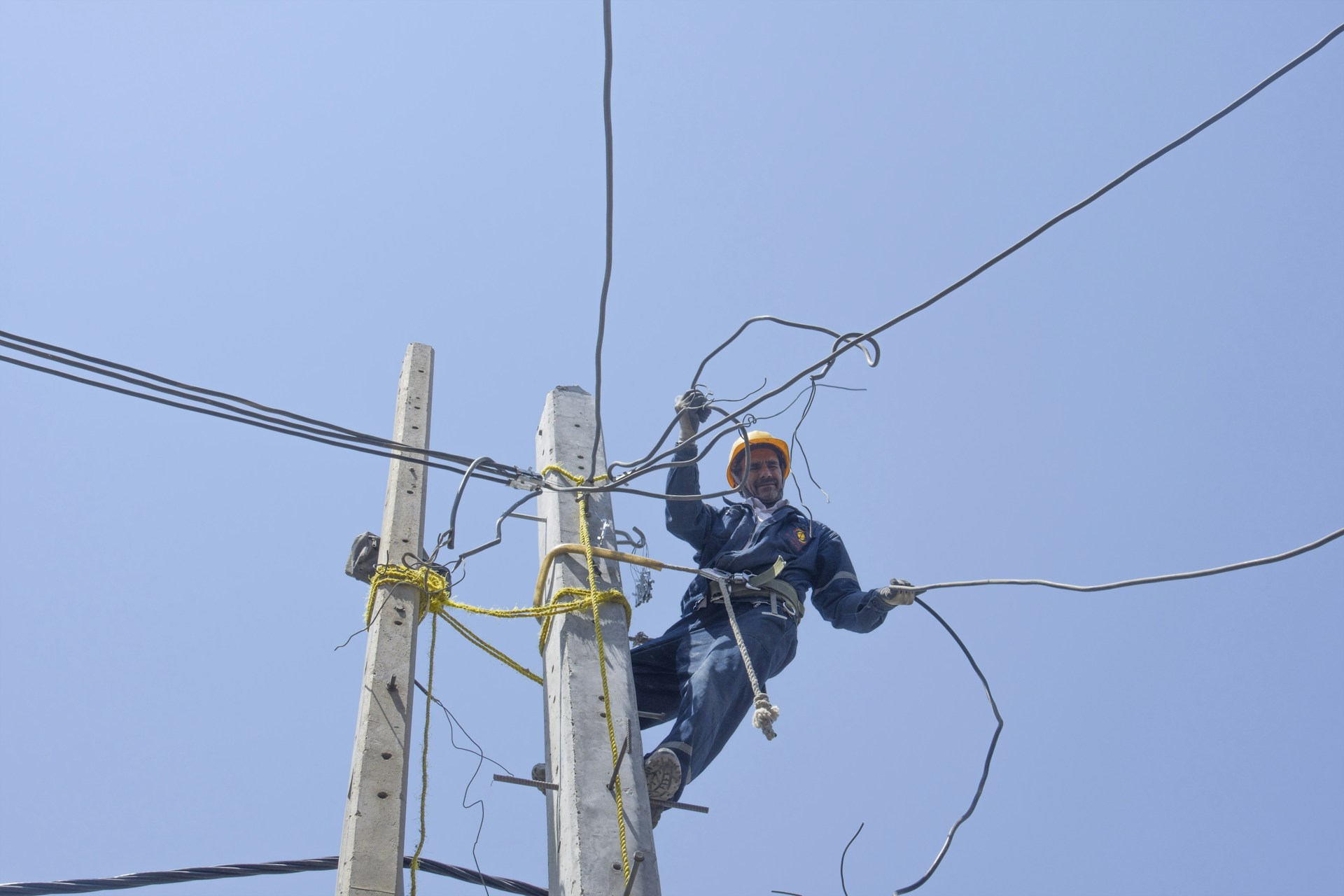 man in black jacket and black pants wearing black helmet on brown electric post during daytime