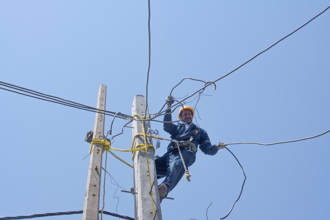 man in black jacket and black pants wearing black helmet on brown electric post during daytime