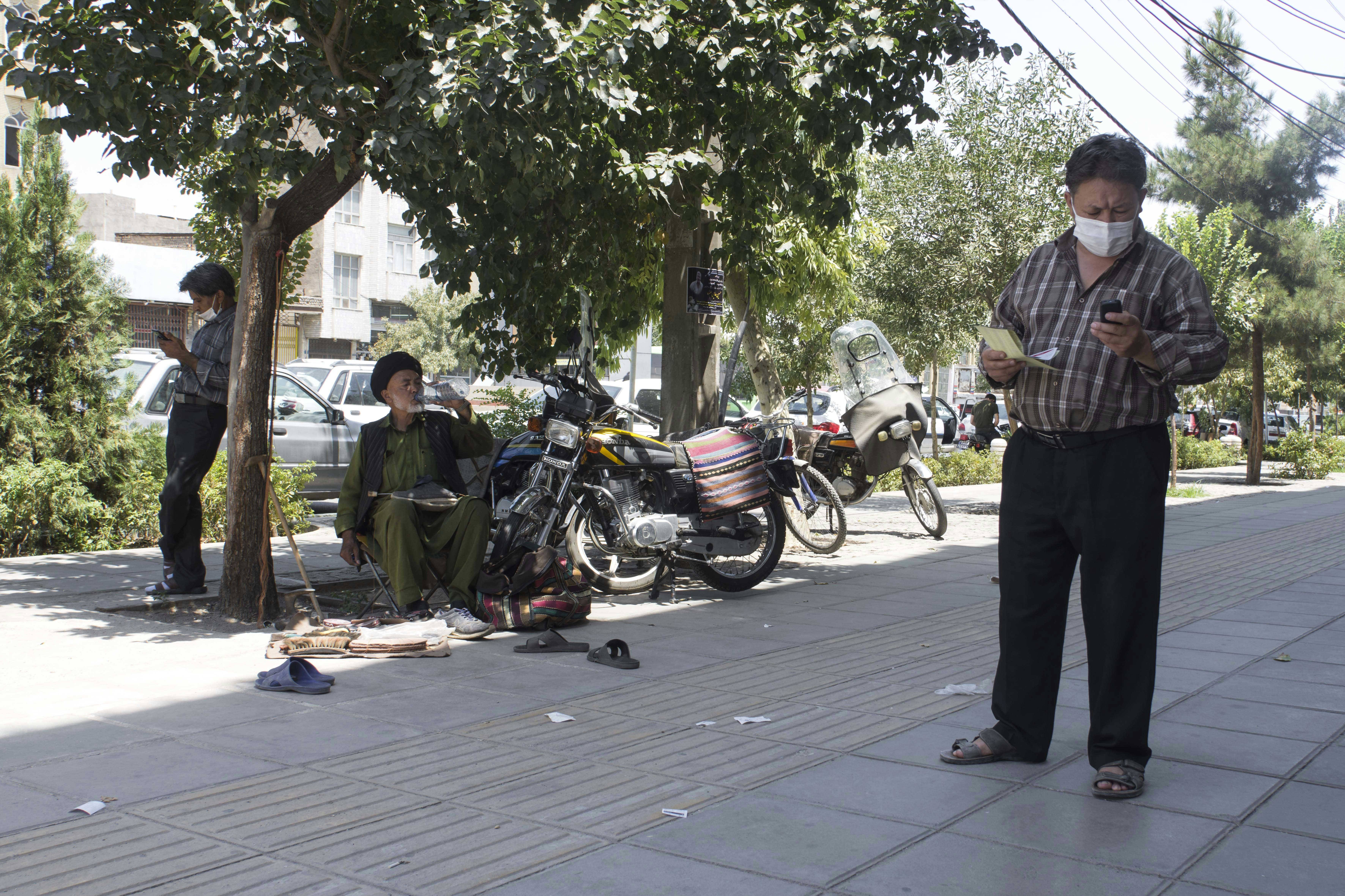 man in brown and green camouflage jacket standing beside motorcycle during daytime