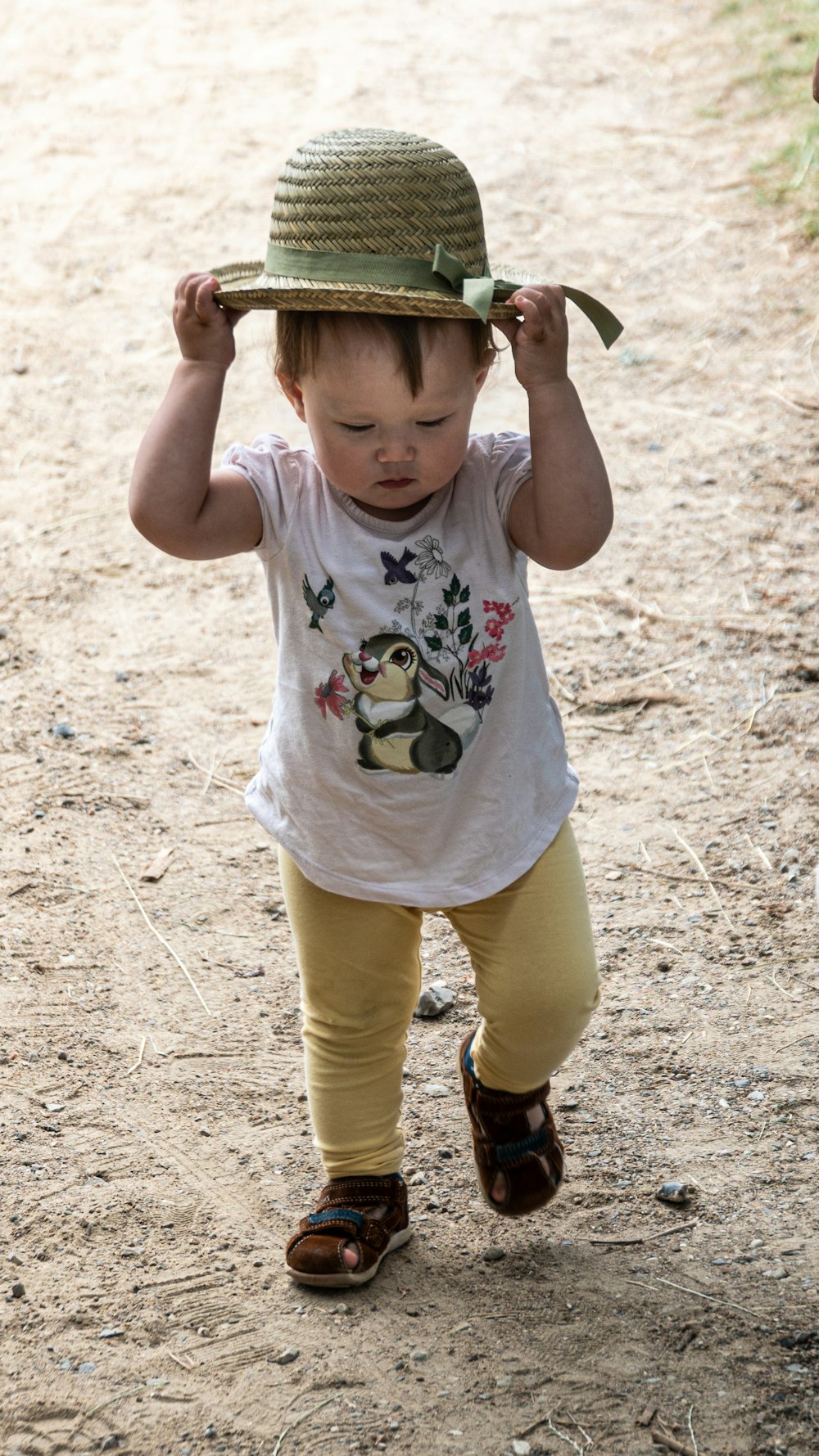 Mädchen in weißem Tanktop und gelben Shorts, die tagsüber auf braunem Sand stehen