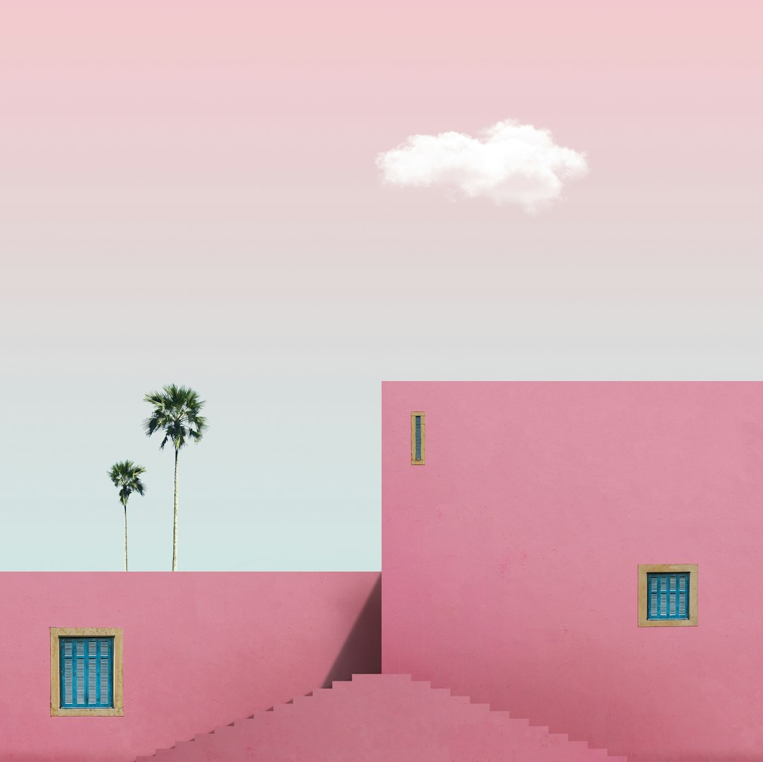 pink concrete building with palm tree in front