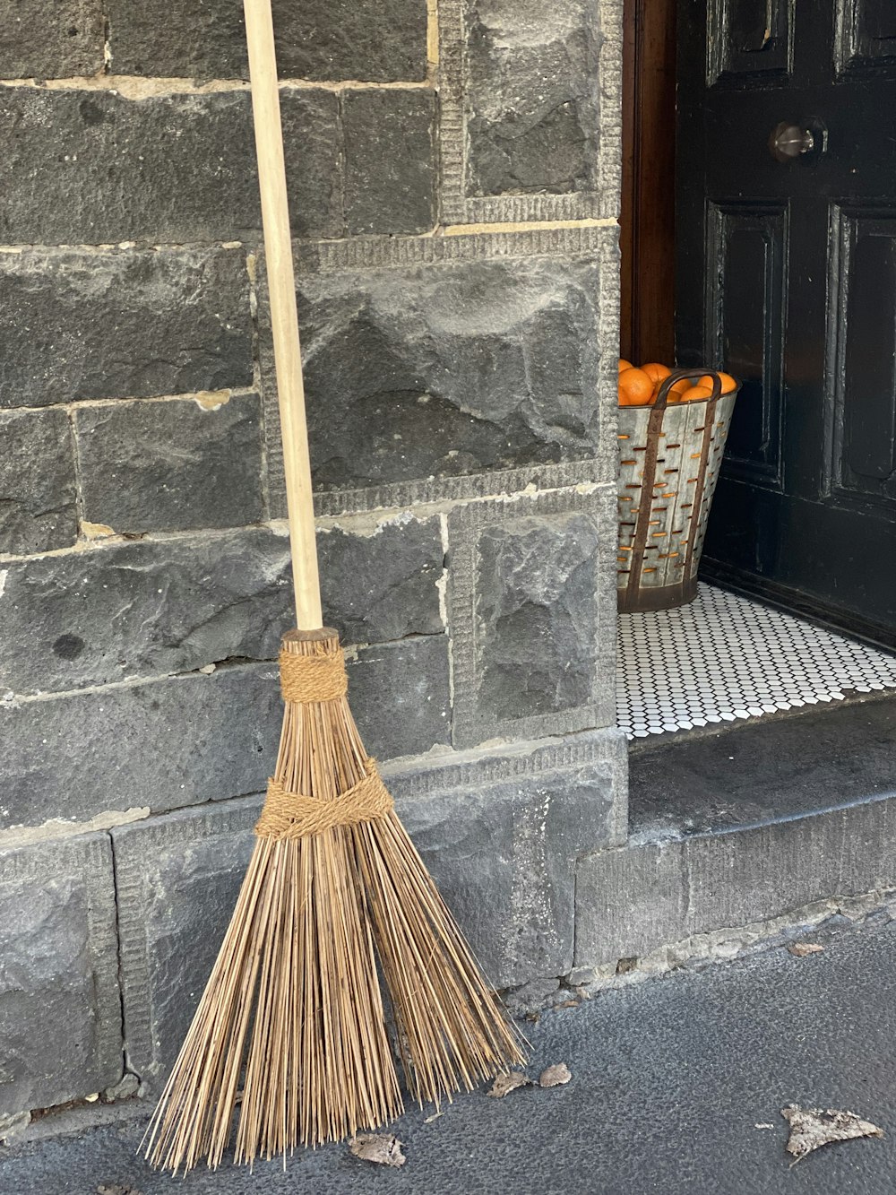 brown broom leaning on gray concrete wall