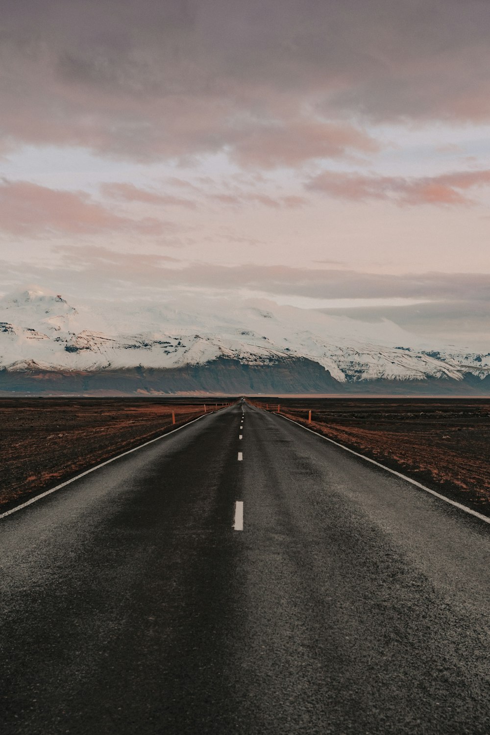 black asphalt road near snow covered mountains during daytime