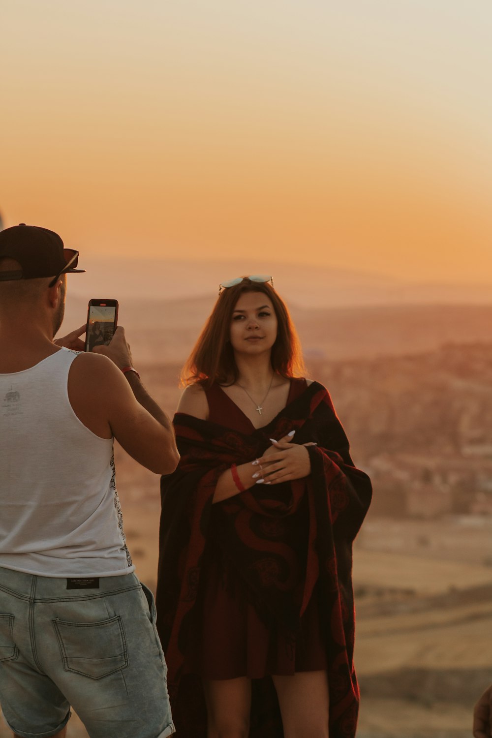 woman in white tank top and red scarf standing beside man in white tank top during