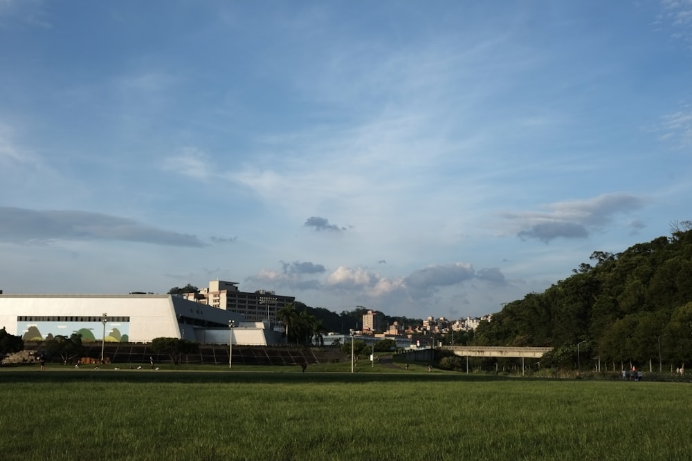 green grass field near white concrete building under blue sky during daytime