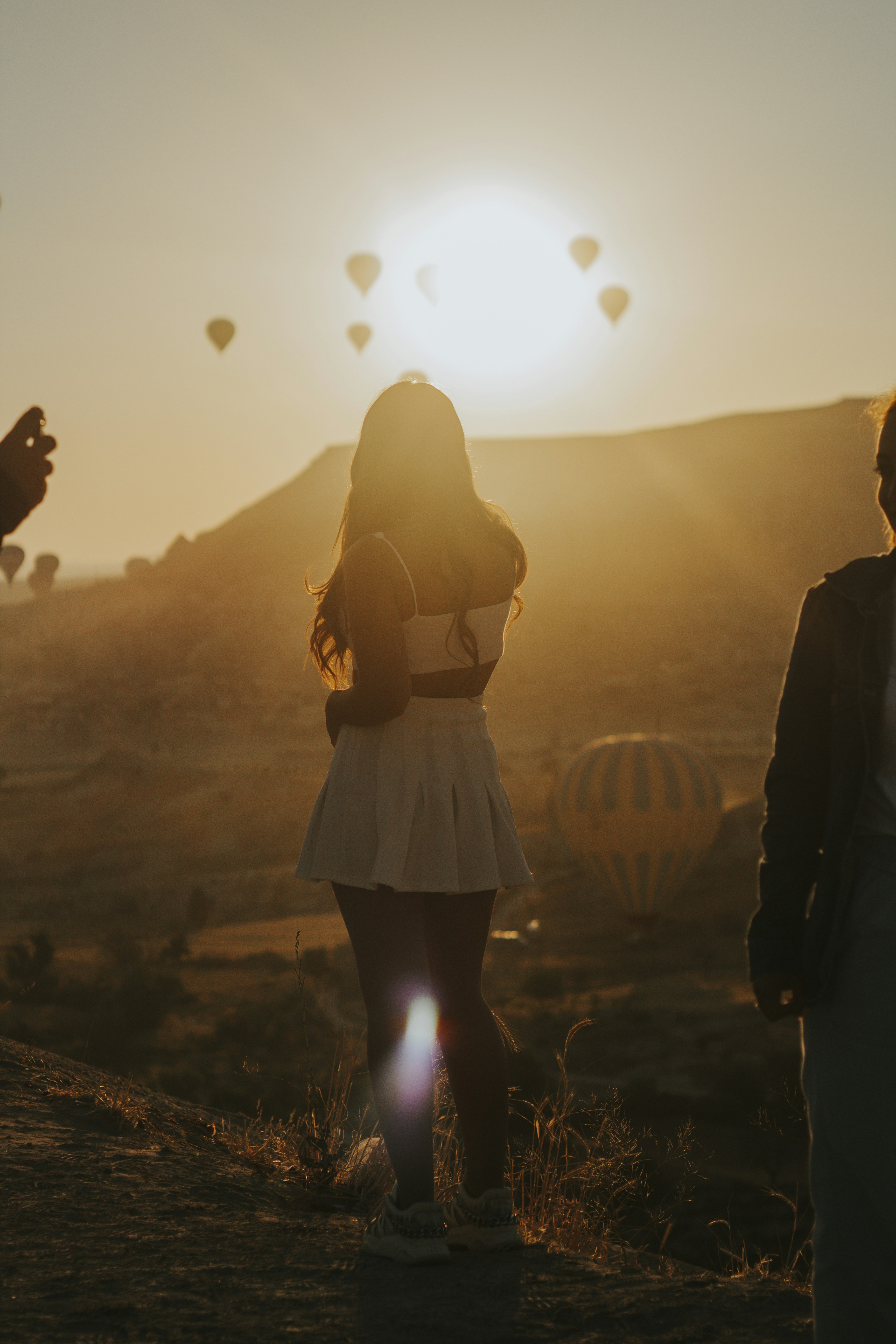 woman in white dress standing on brown sand during sunset