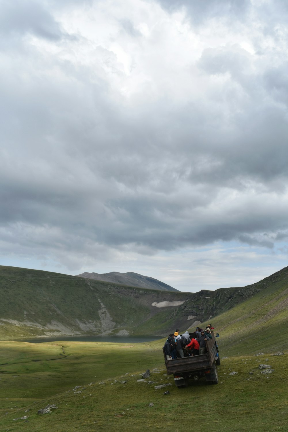 people on green grass field near green mountains under white cloudy sky during daytime