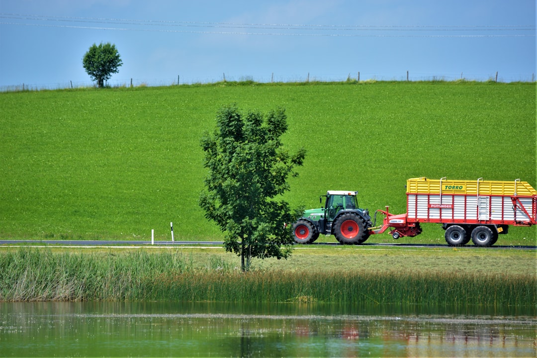 red and yellow tractor on green grass field during daytime