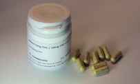 white plastic bottle with brown tablets