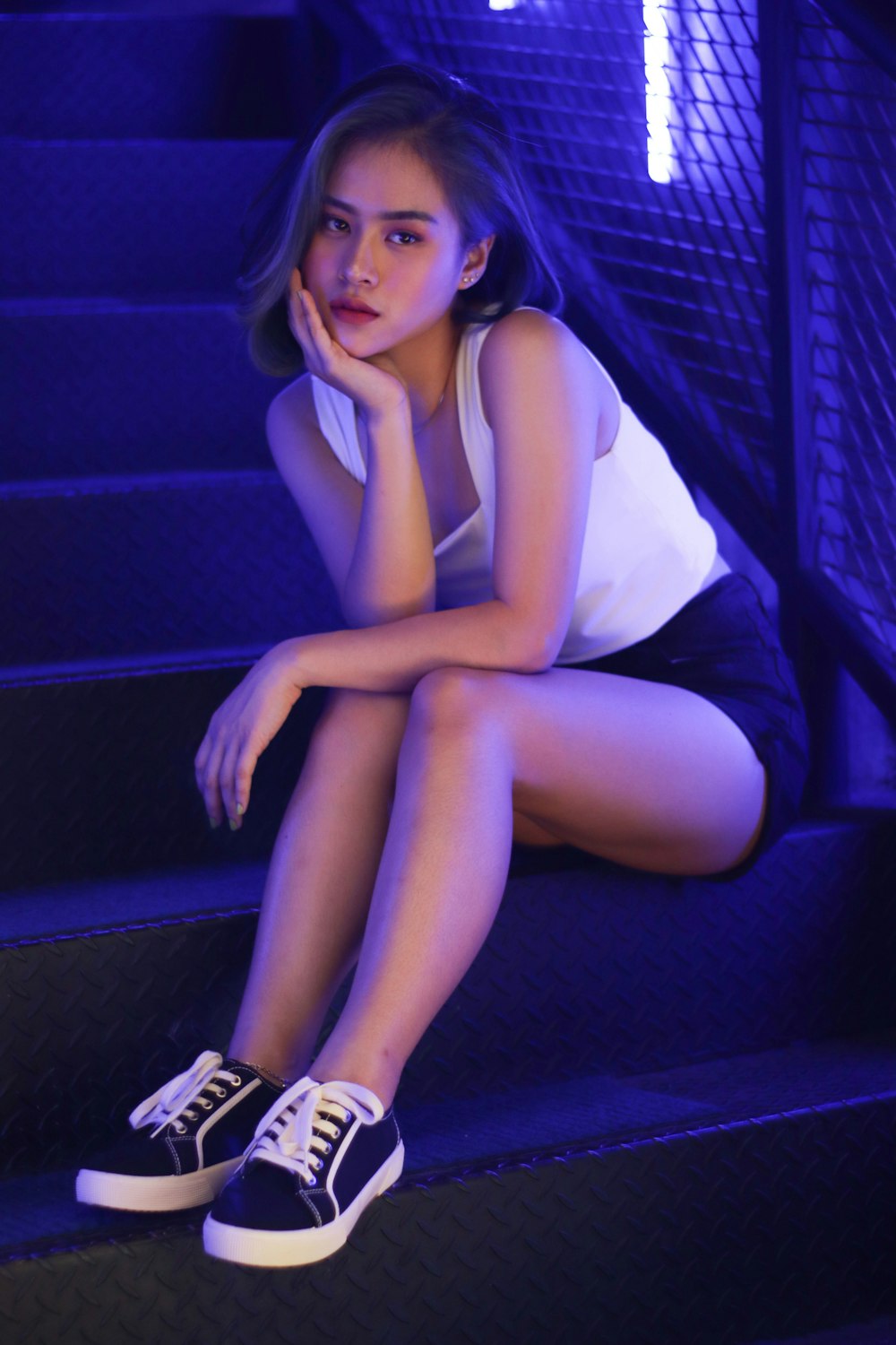 woman in white tank top and black shorts sitting on purple couch