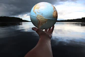 Hands holding a small globe with ocean waves painted on it, symbolizing care for the planet’s waters.