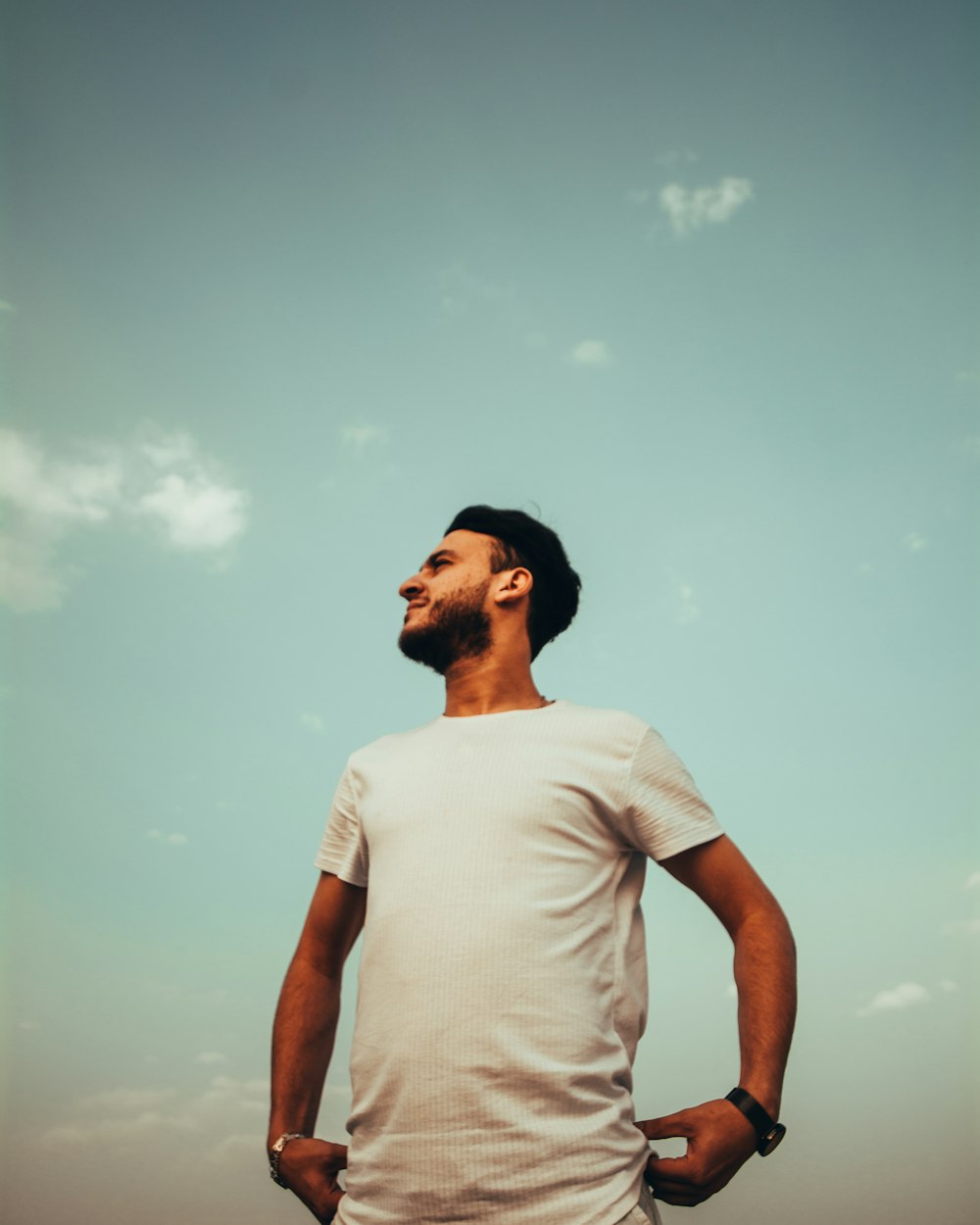 man in white crew neck t-shirt standing under blue sky during daytime