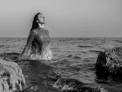 Athlete emerging from the water with Cabo San Lucas rocky coastline in the background.