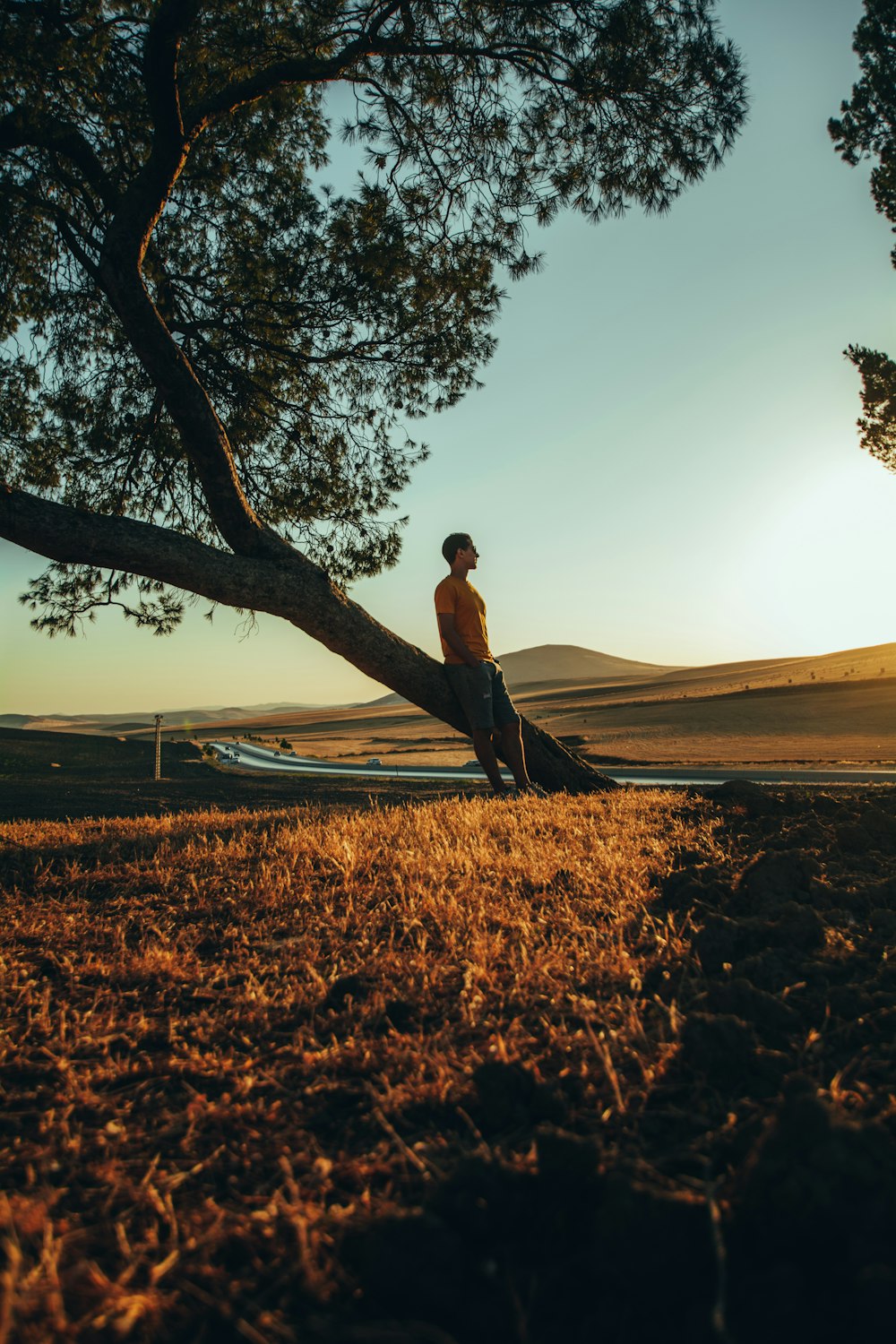 man in brown jacket standing on brown grass field during sunset