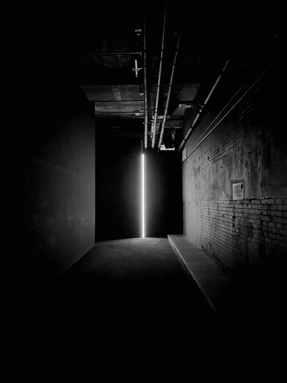 grayscale photo of tunnel with light