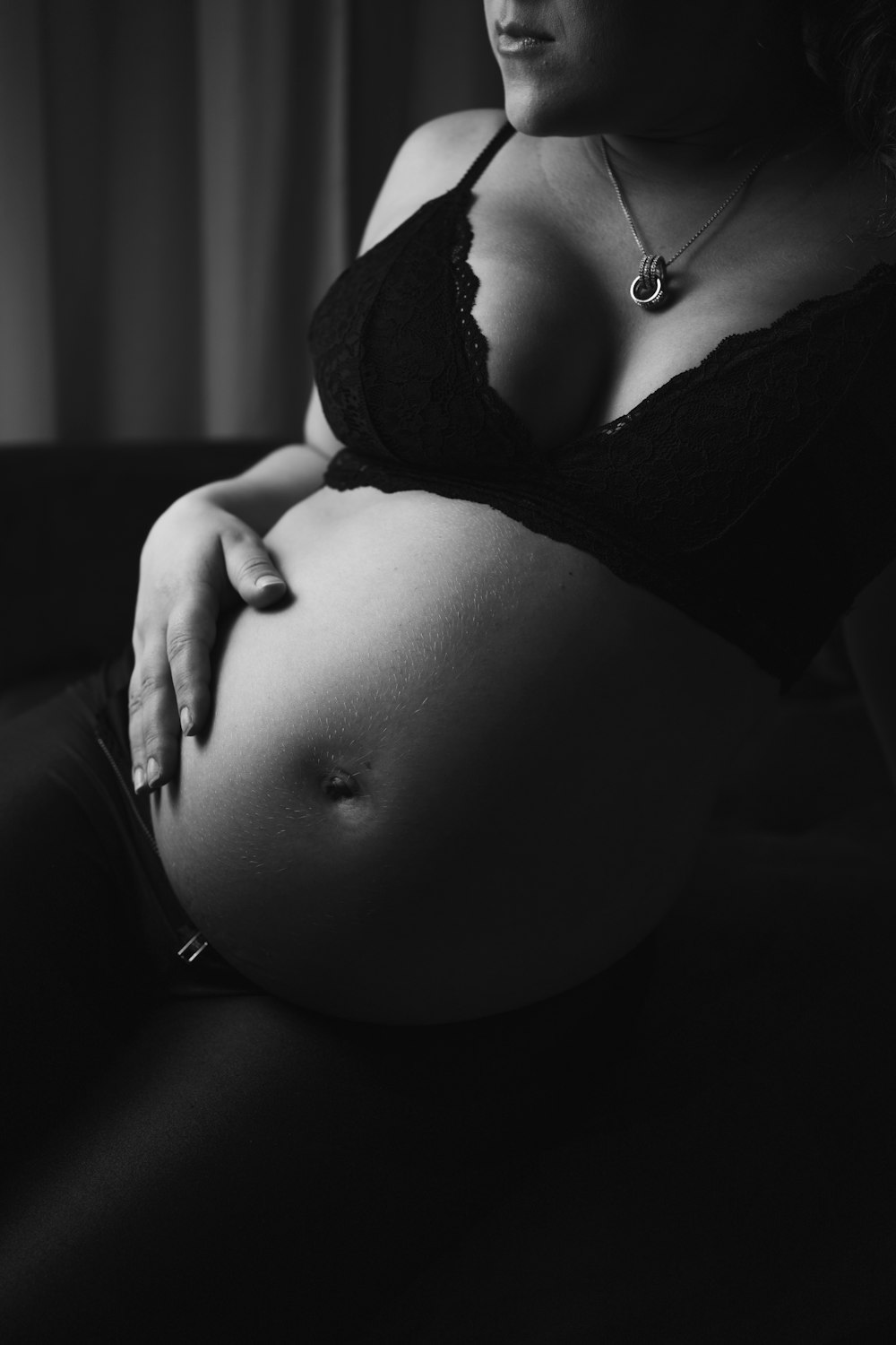 grayscale photo of pregnant woman wearing black brassiere