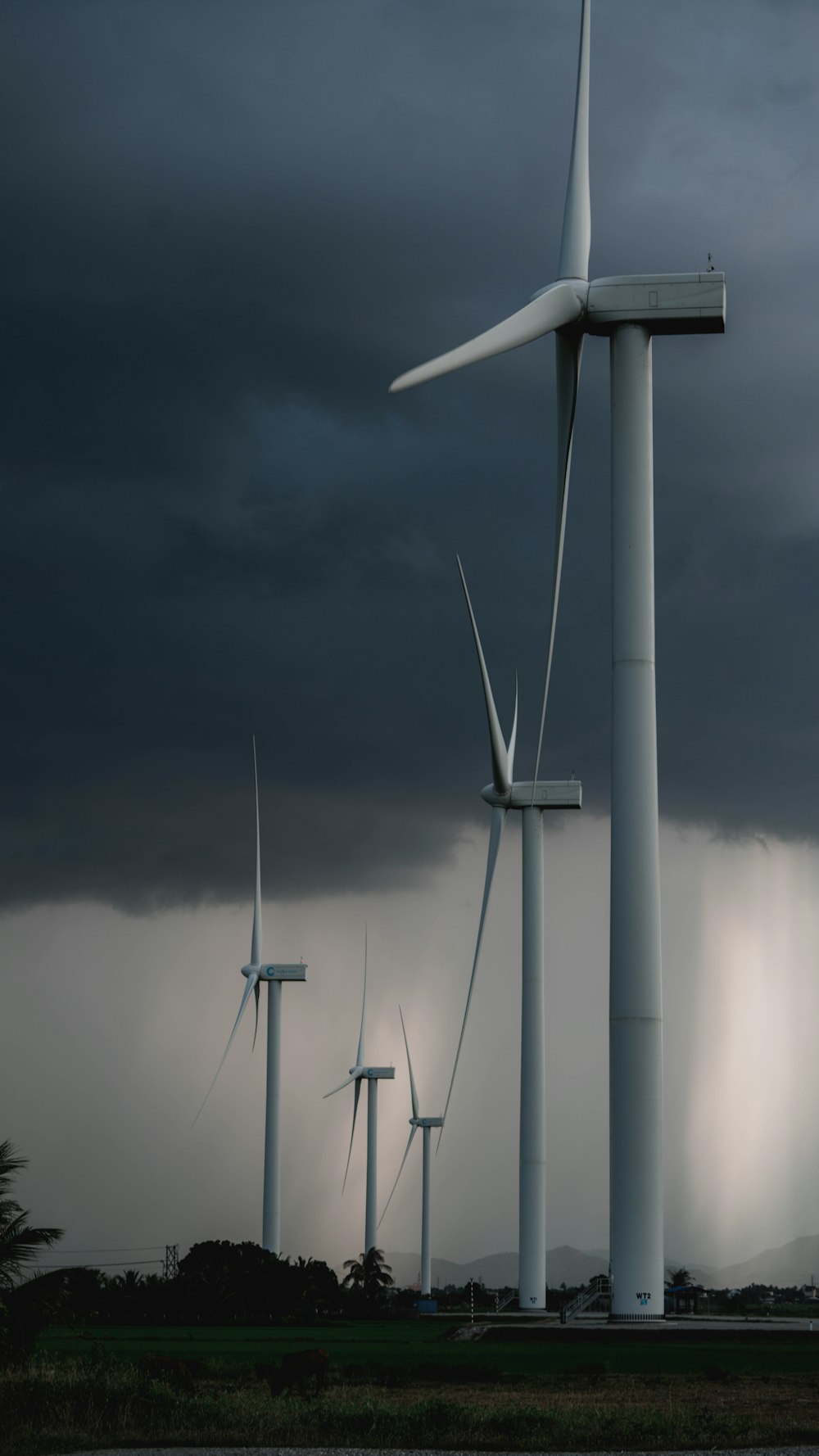 white wind turbine under gray sky