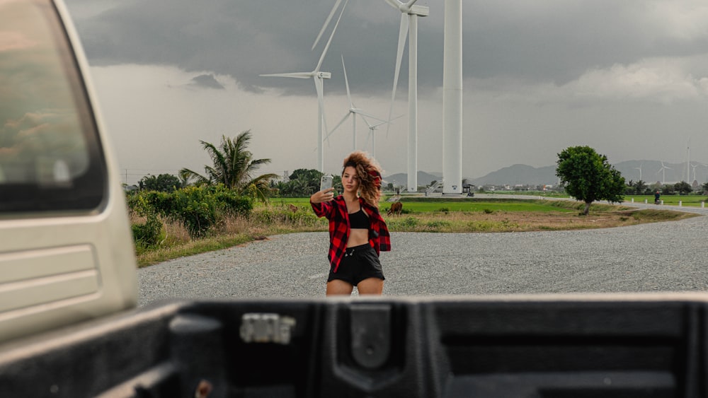 woman in red shirt and black shorts sitting on black car hood during daytime