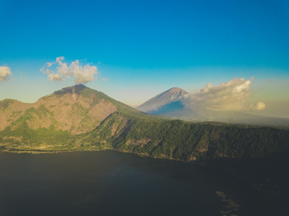 green and brown mountain beside blue sea under blue sky during daytime