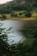 A serene view of a lush green landscape with a tranquil lake in the foreground.