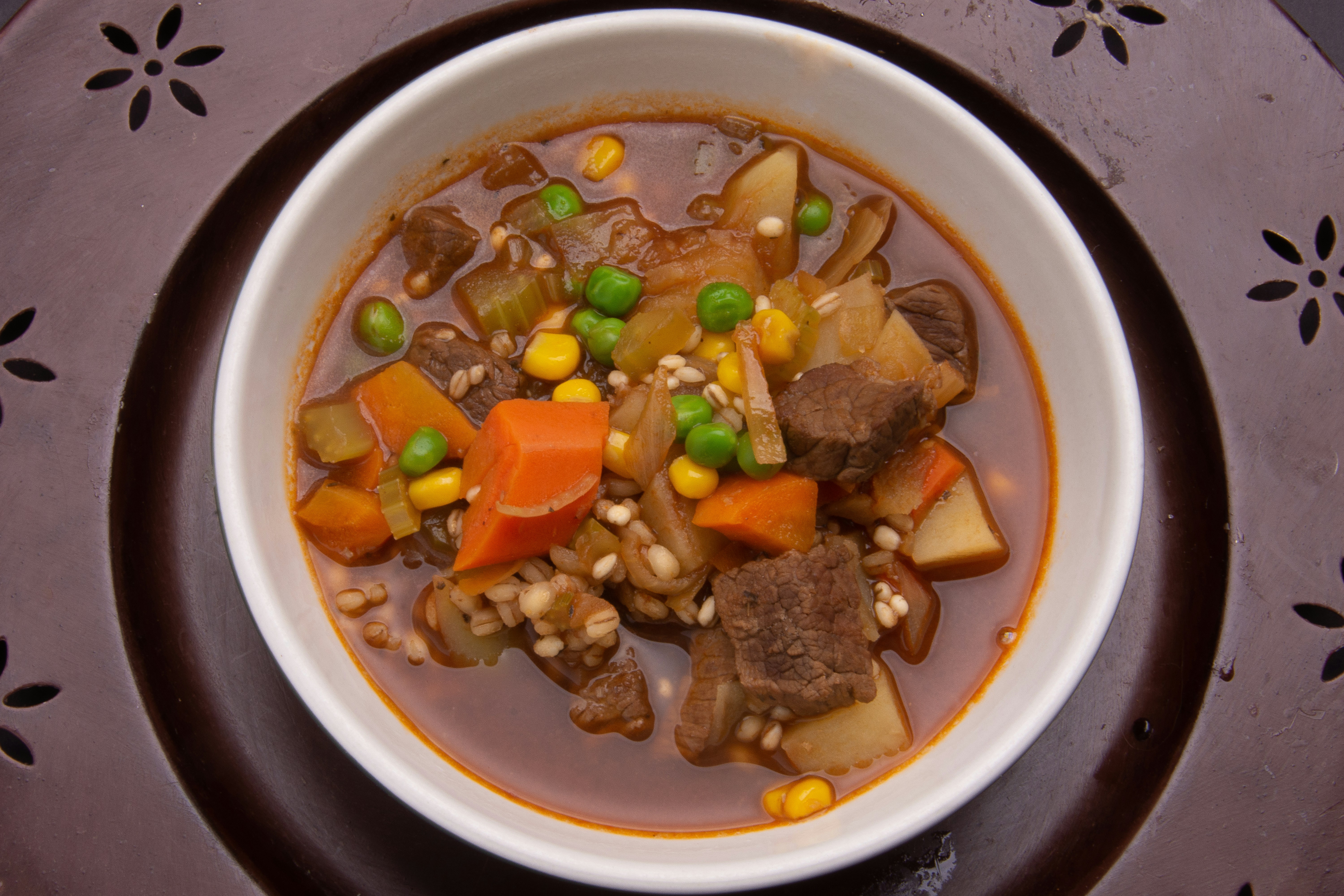 Hearty beef stew with vegetables in a deep bowl served with warm cornbread
