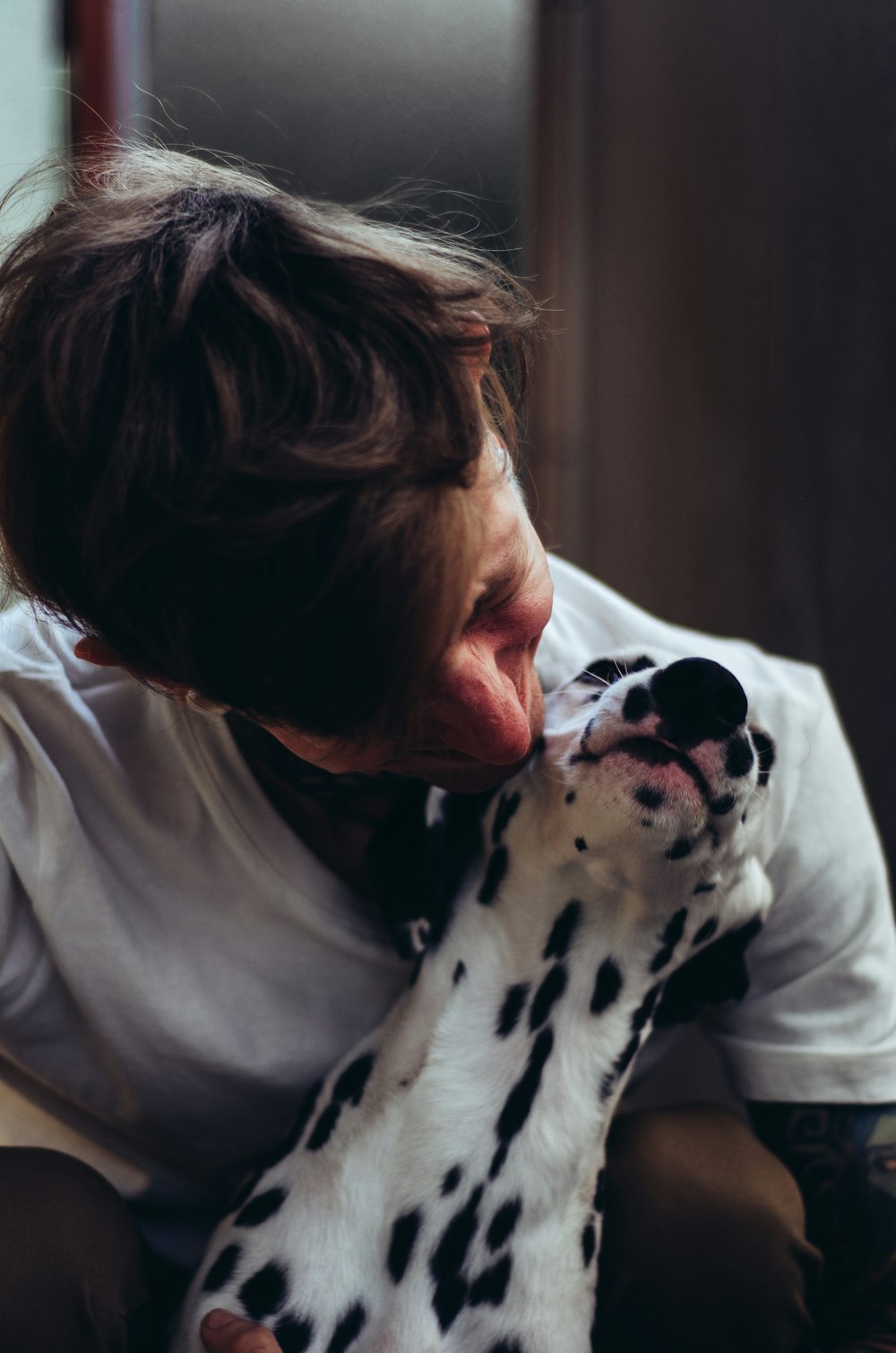 Mujer con camisa blanca abrazando perro dálmata