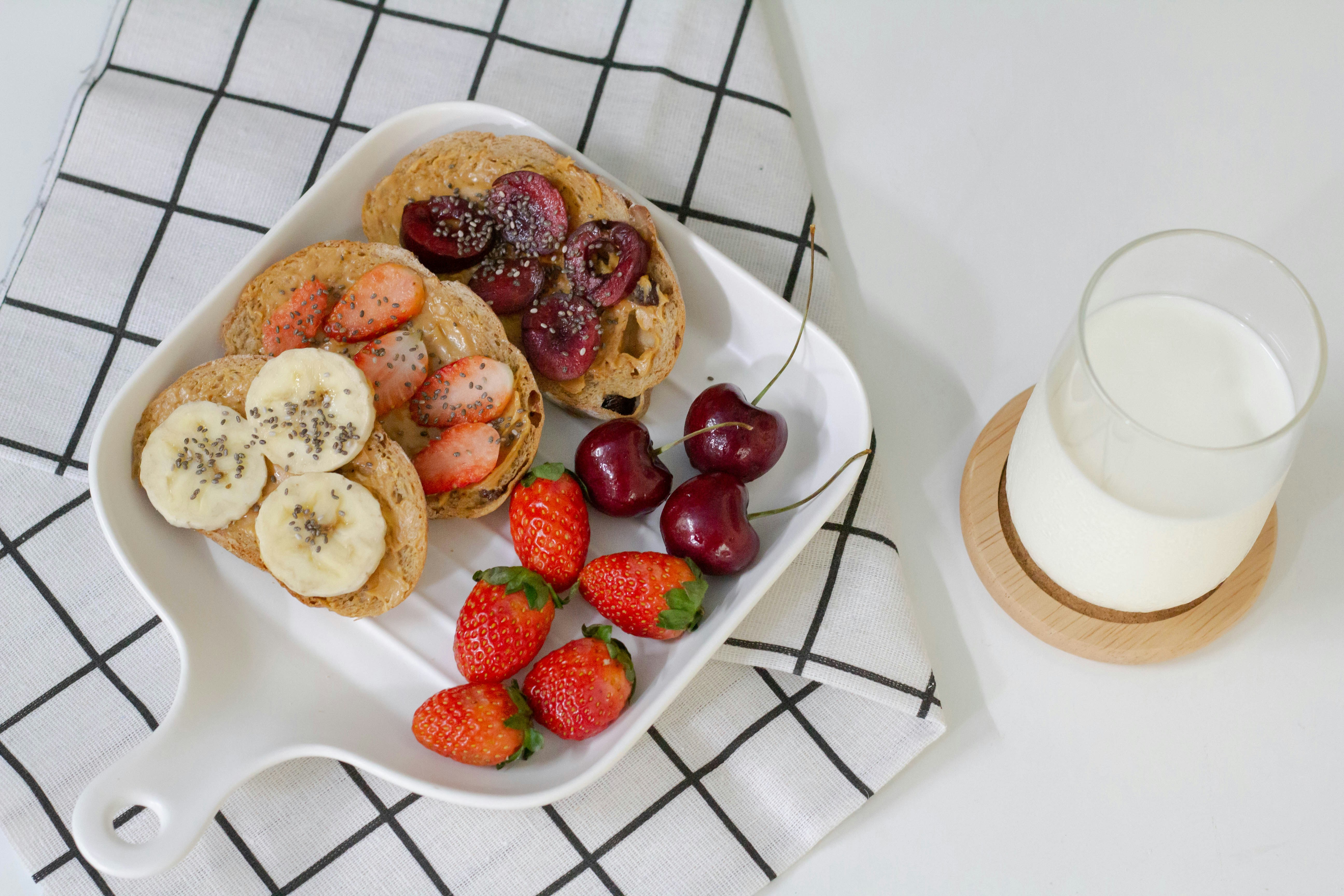 Waffles with banana and strawberries beside a glass of milk