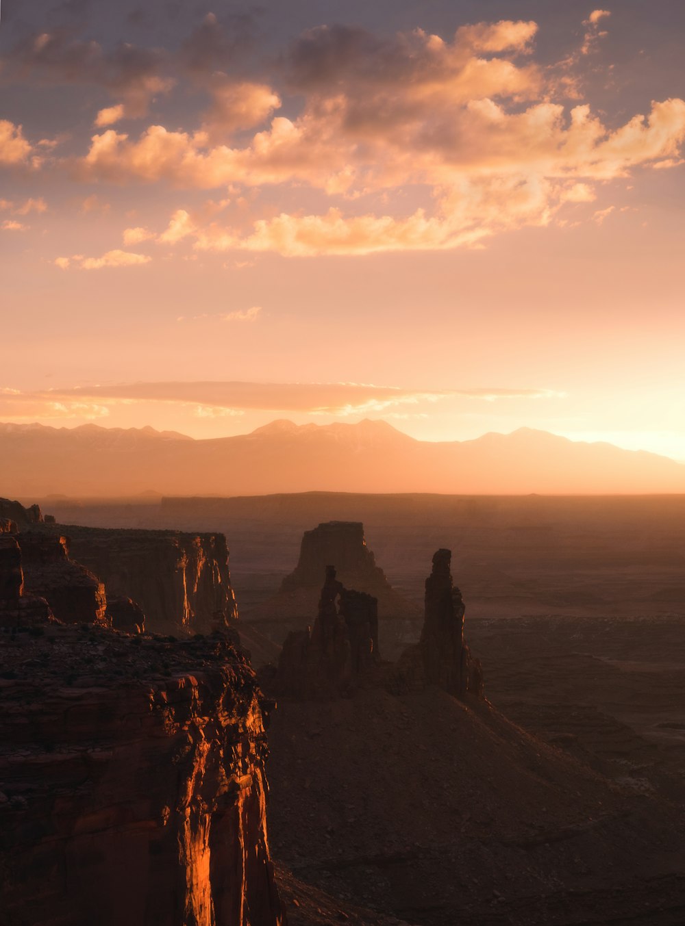 silhouette of 2 person standing on rock formation during sunset