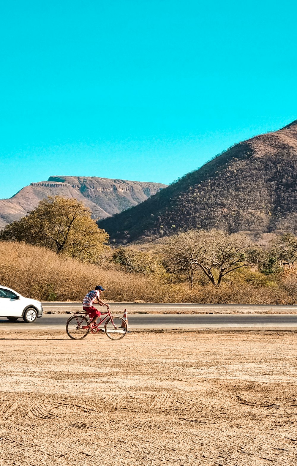 man in red shirt riding bicycle on road during daytime